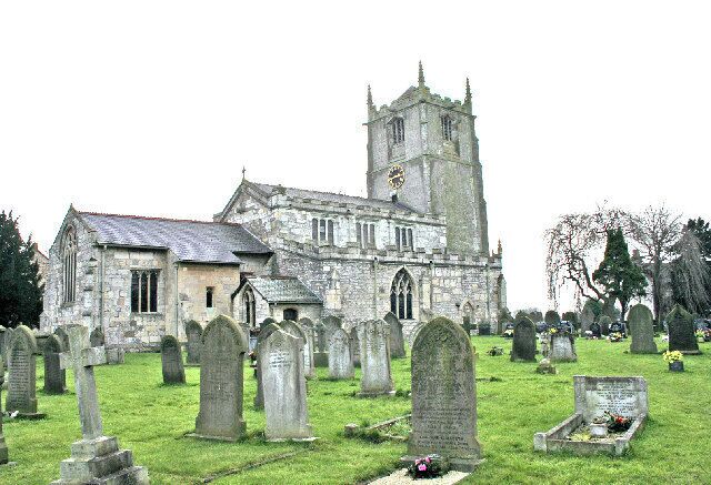 A church with a tall tower and a graveyard with numerous headstones.