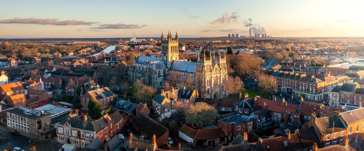 A historic town with a prominent cathedral, a river, and industrial structures in the background.