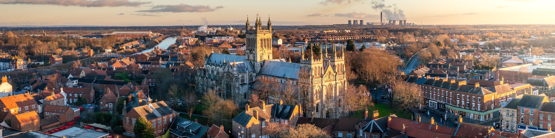 A historic town with a prominent cathedral, a river, and industrial structures in the background.