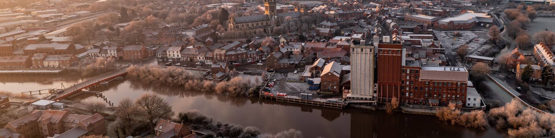 A river flowing through a town with historic buildings and a prominent church tower.