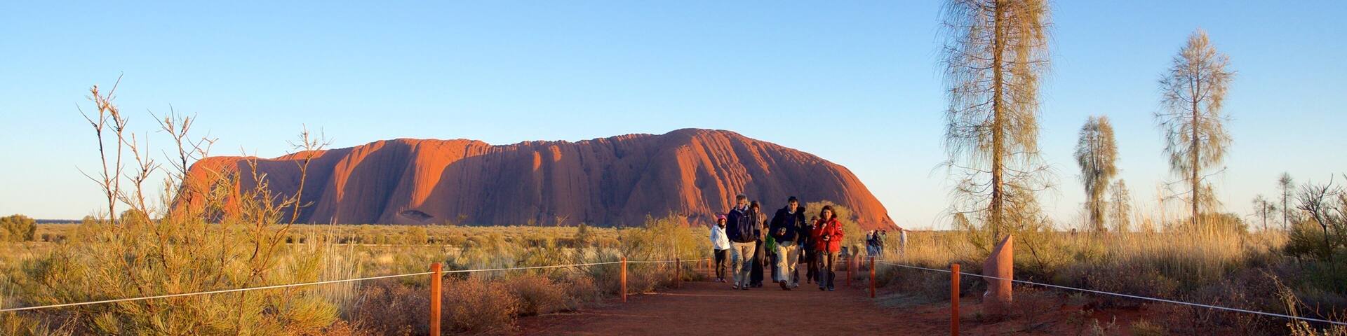 Uluru showing desert views and landscape views as well as a small group of people