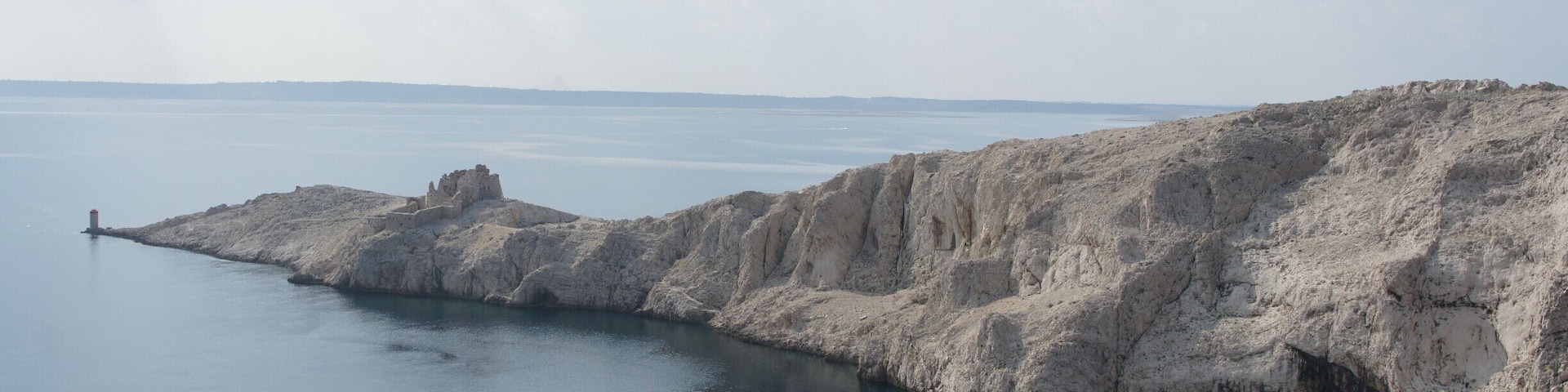 A coastal landscape with a rocky outcrop and calm water.