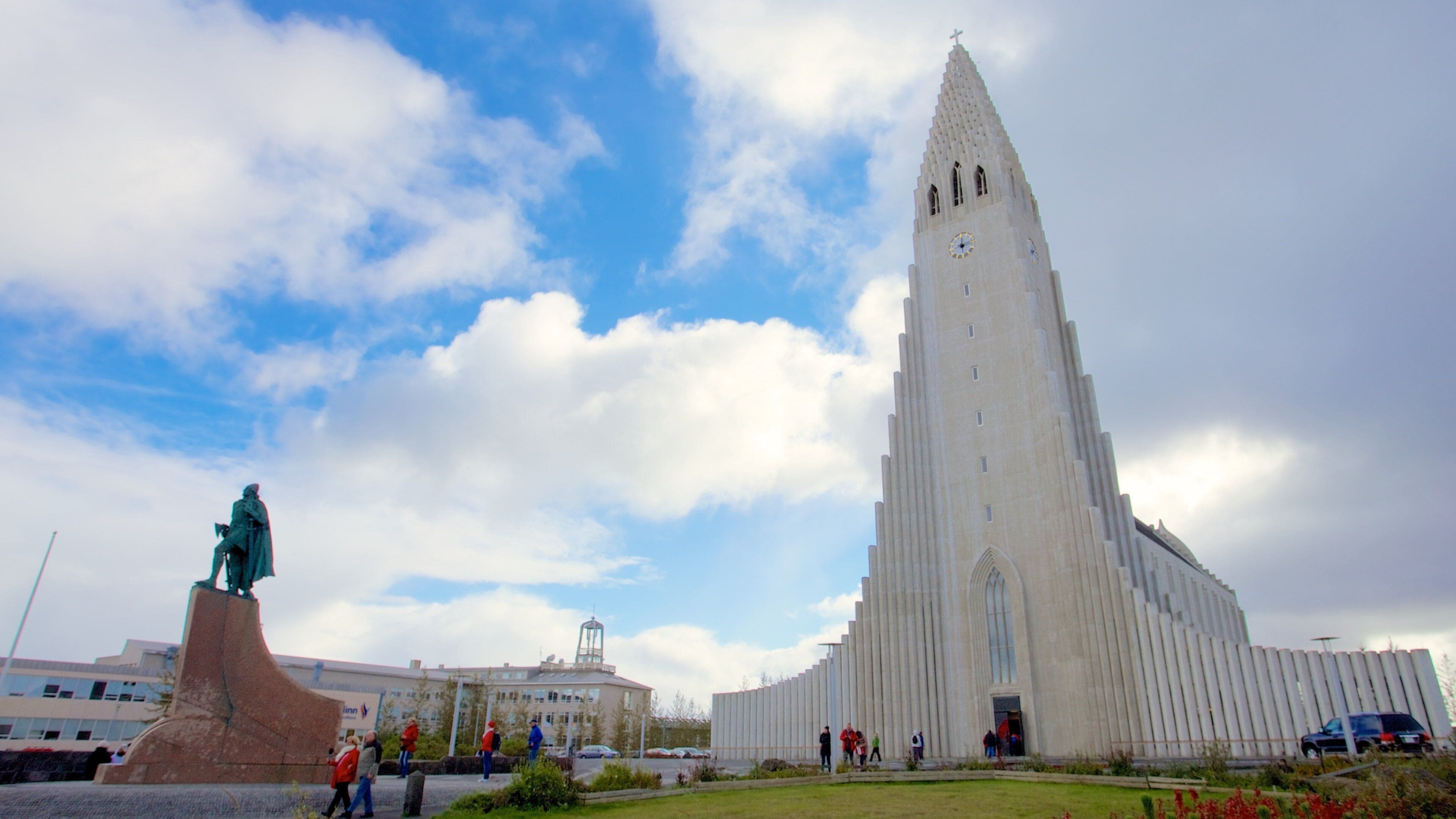 A tall white church with a pointed steeple and a statue in front.