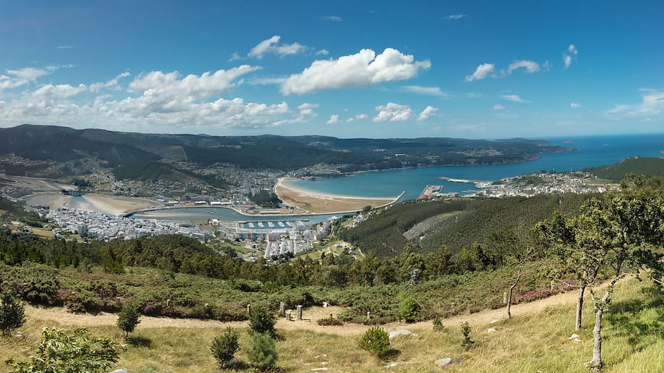A coastal city with a bay, mountains, and a clear sky.
