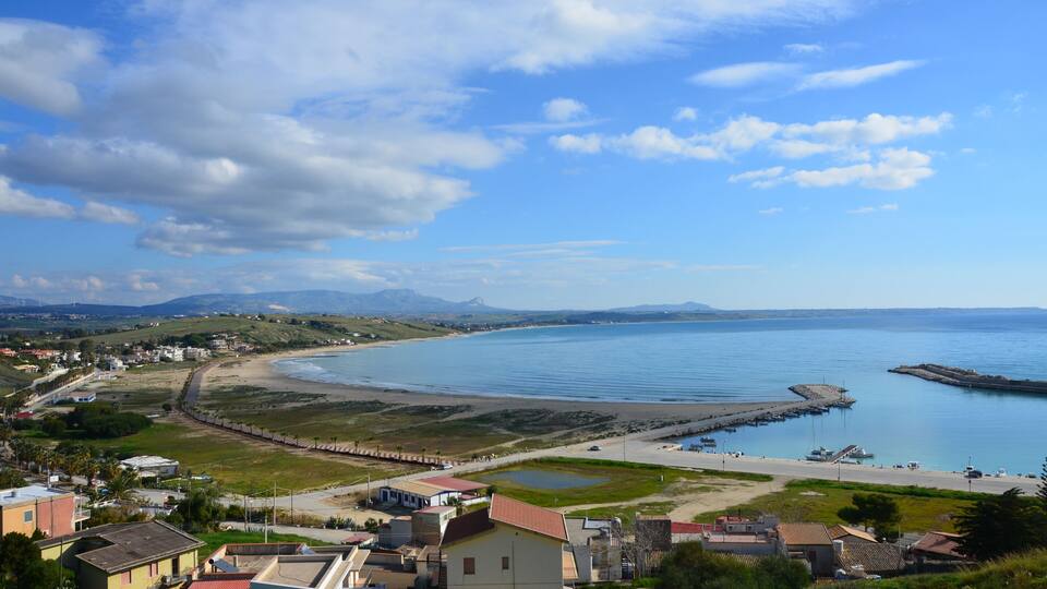 A coastal town with a beach, a pier, and a mountainous backdrop.