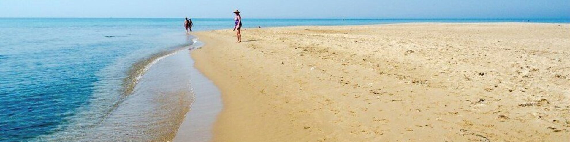A wide sandy beach with gentle waves lapping at the shore.
