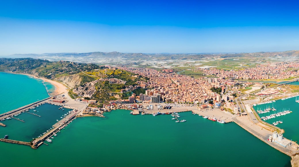 A coastal city with a marina, a beach, and a mountainous backdrop.