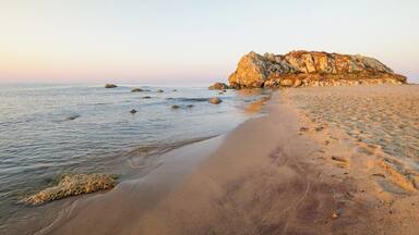 A sandy beach with a rocky outcrop in the distance.