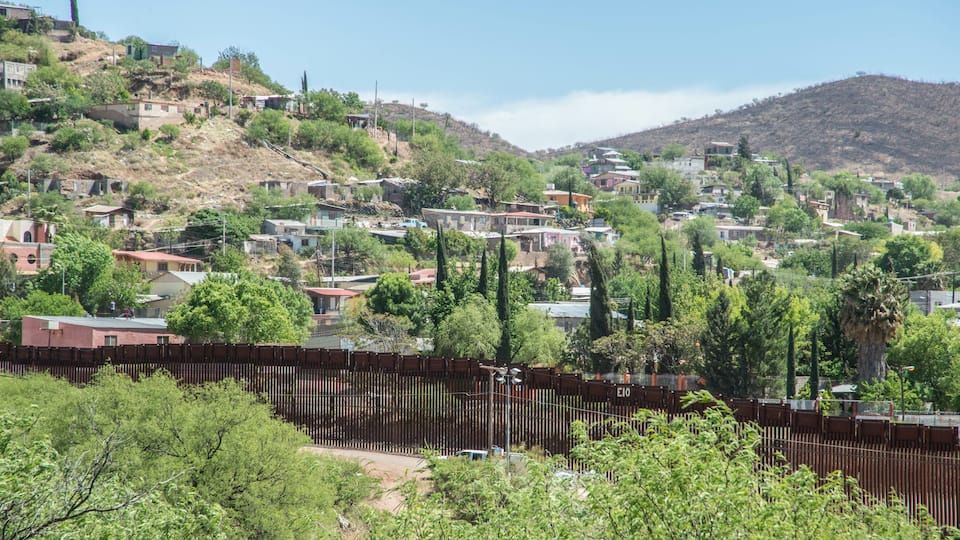 A hillside town with houses, trees, and a fence.