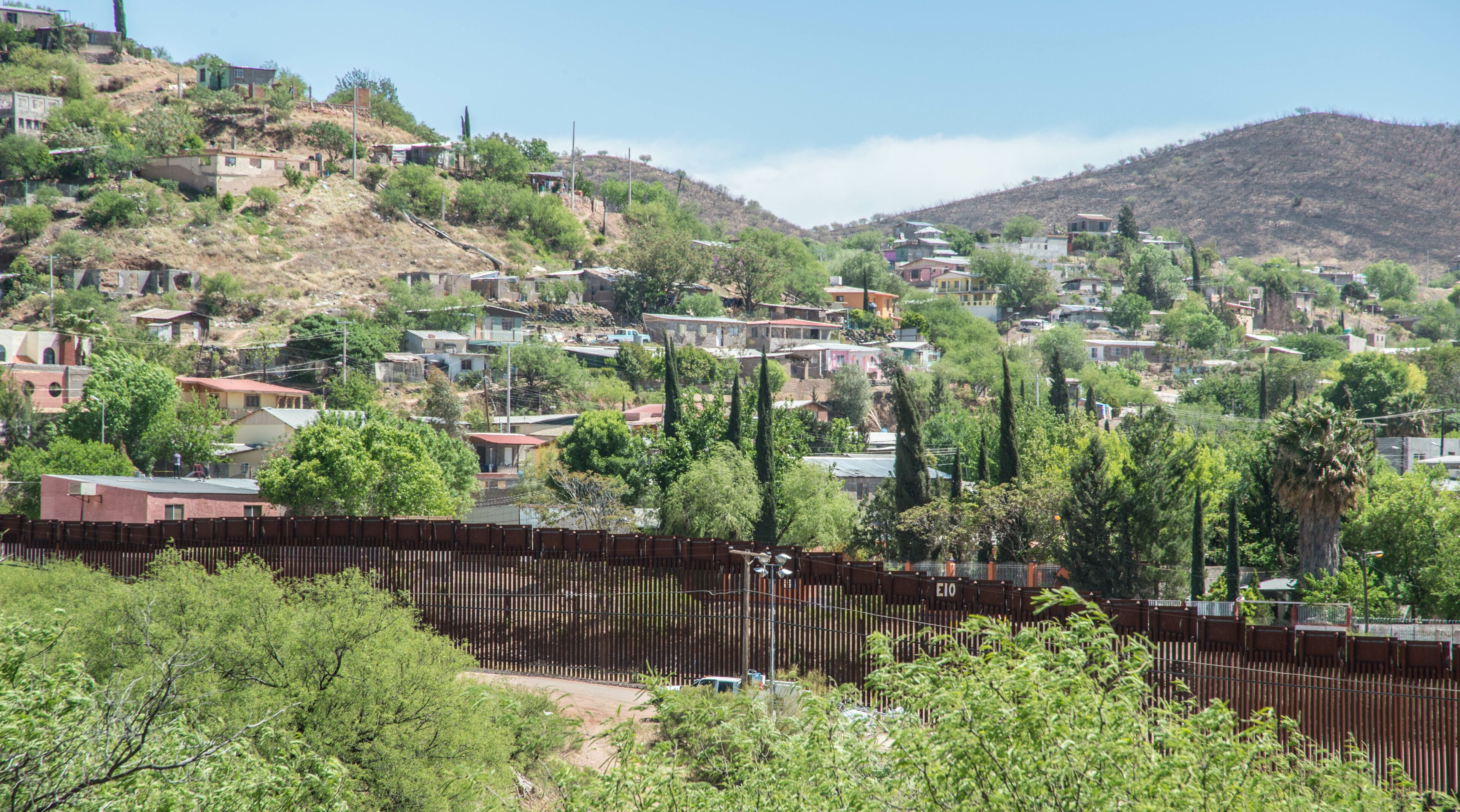 A hillside town with houses, trees, and a fence.