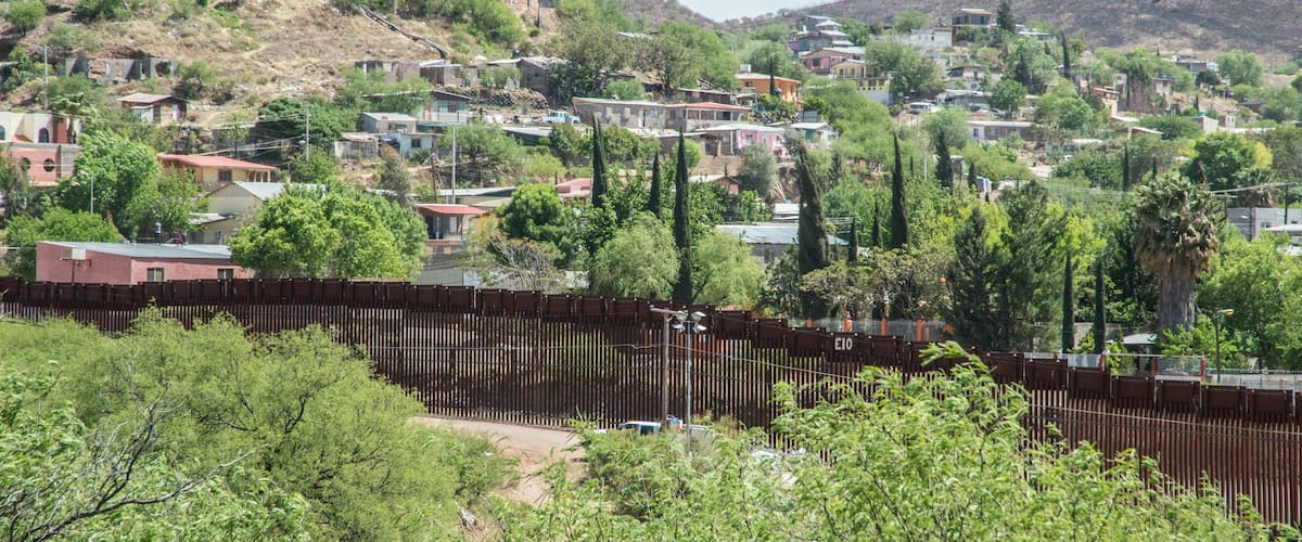 A hillside town with houses, trees, and a fence.