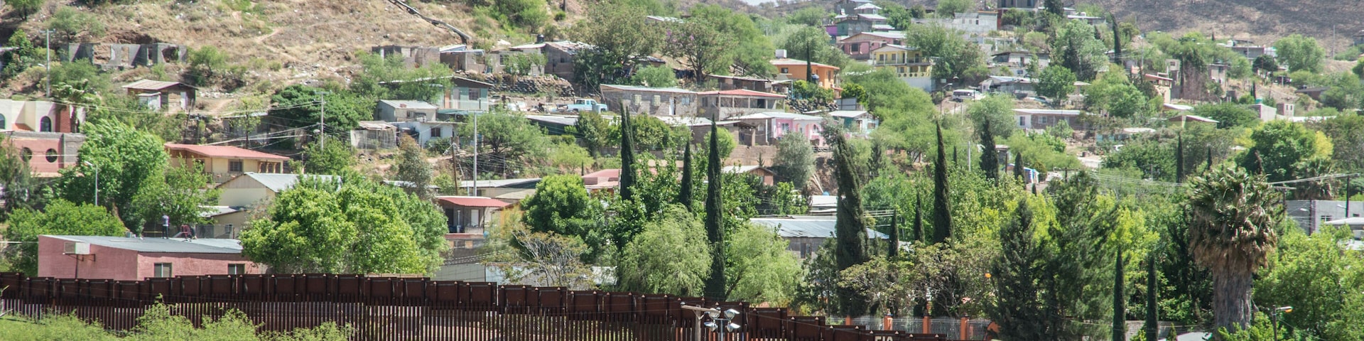 A hillside town with houses, trees, and a fence.