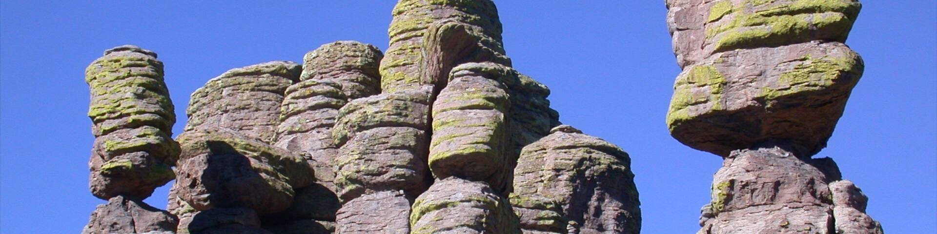 A rock formation with layered rock columns and a clear blue sky.