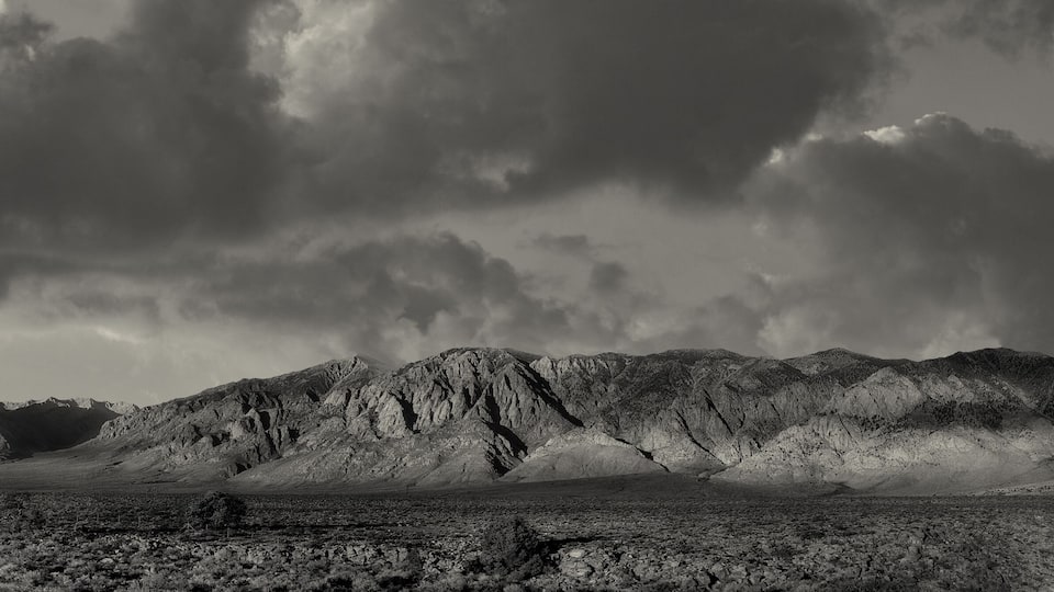 A rugged mountain range with a barren landscape and a cloudy sky.