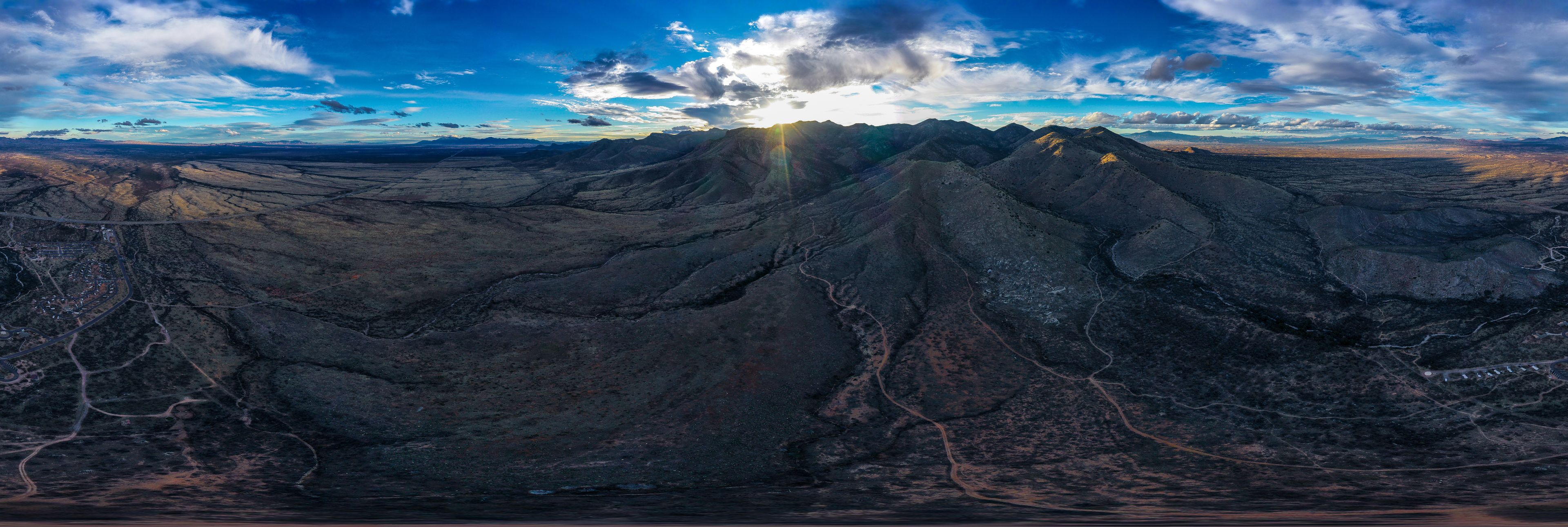 Aerial view and panorama of Arizona mountain ranges during sunset with clouds and sun