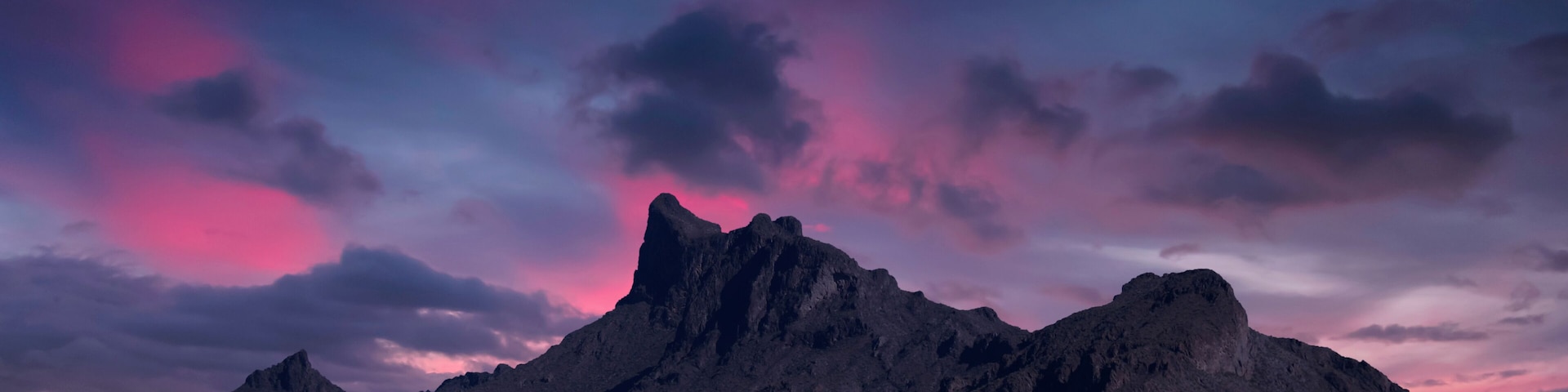 A mountain range with a dramatic sky at sunset.
