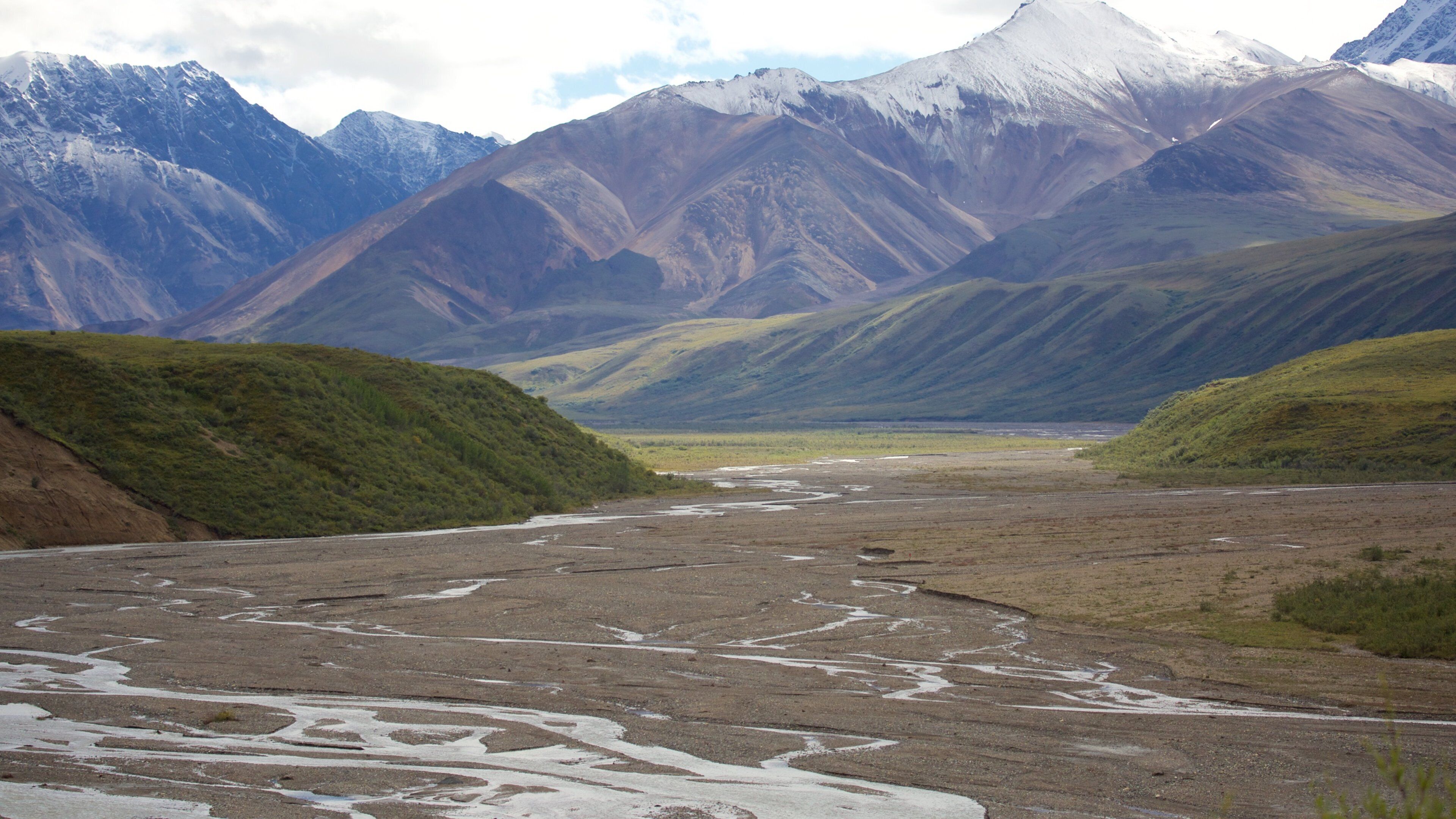 A river flowing through a valley with mountains in the background.