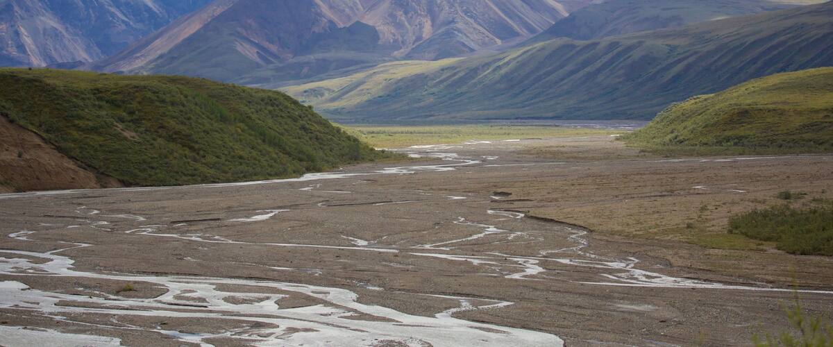 A river flowing through a valley with mountains in the background.