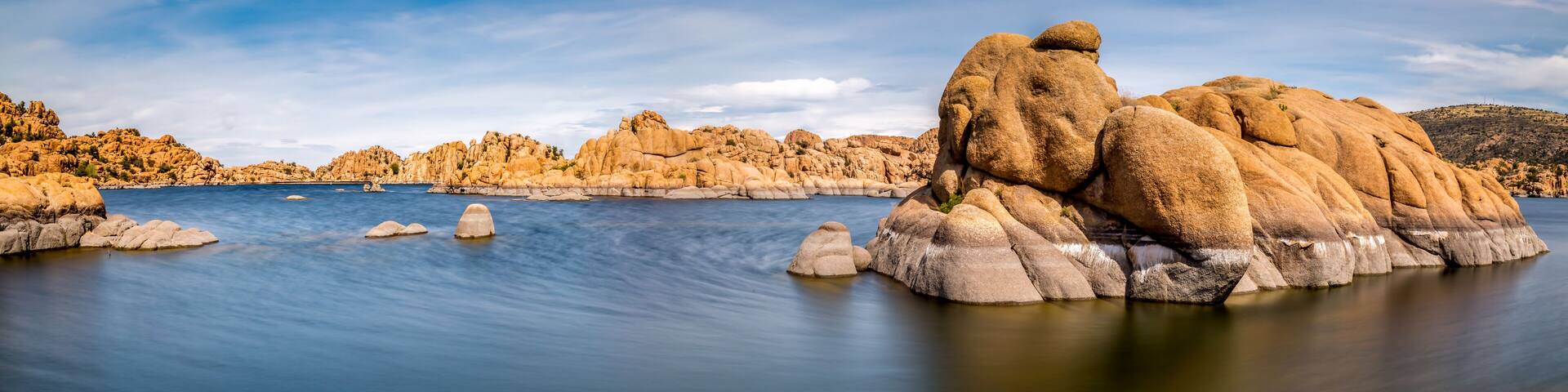 A calm lake surrounded by large boulders and rocky hills.