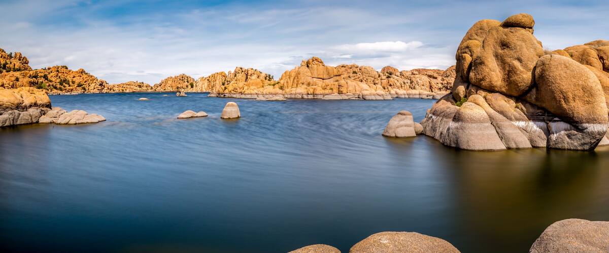 A calm lake surrounded by large boulders and rocky hills.