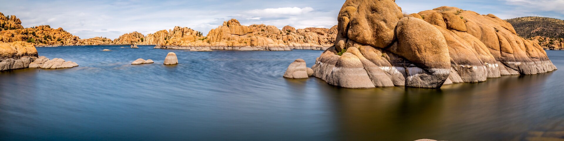 A calm lake surrounded by large boulders and rocky hills.