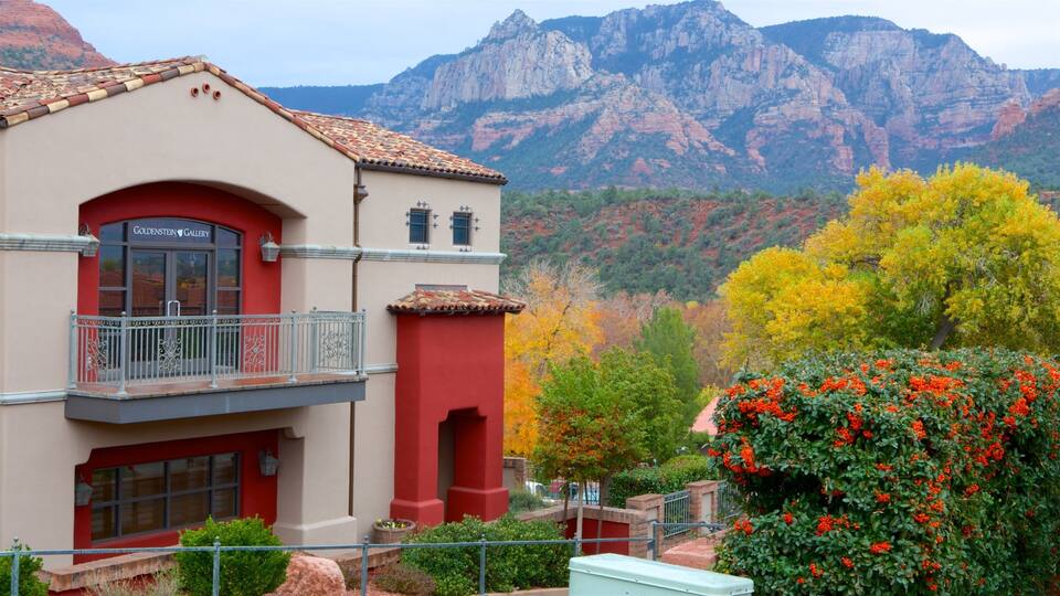 A building with a red and beige facade, a balcony, and a mountainous backdrop.