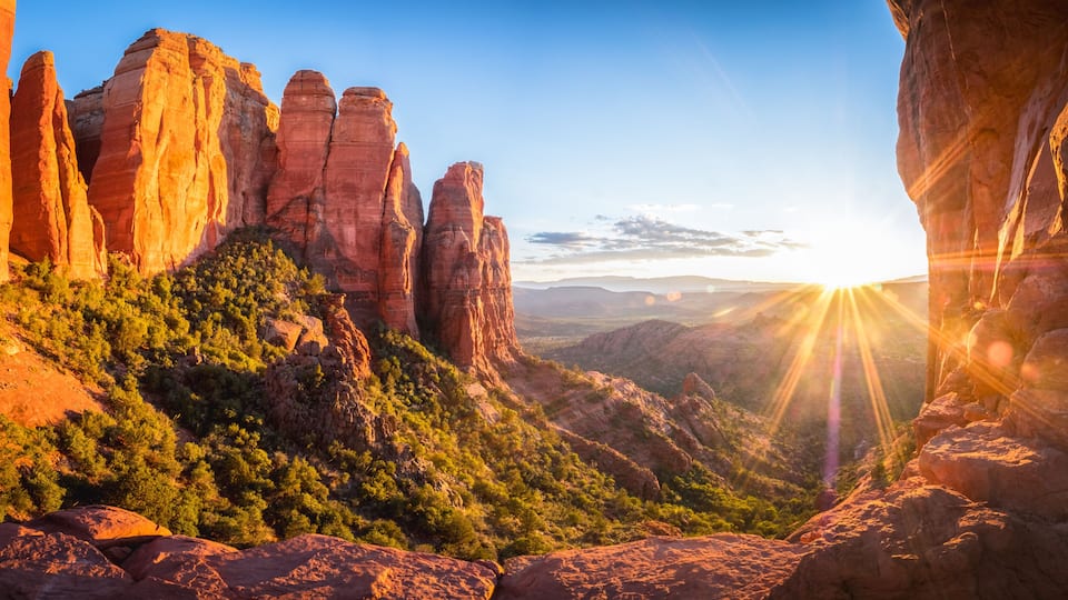 A canyon with red rock formations and a valley.