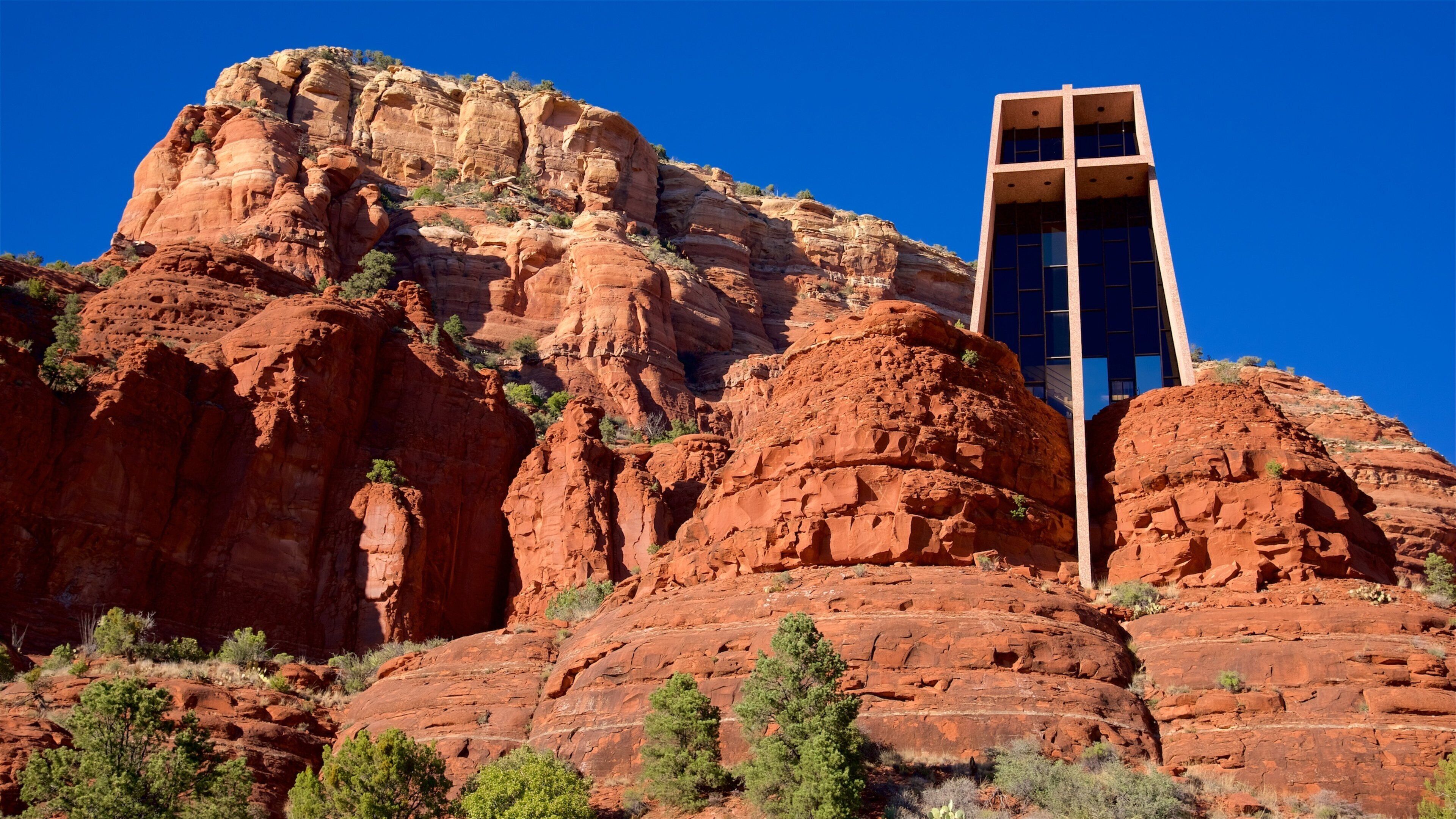 A modern building with a glass facade among red rock formations.
