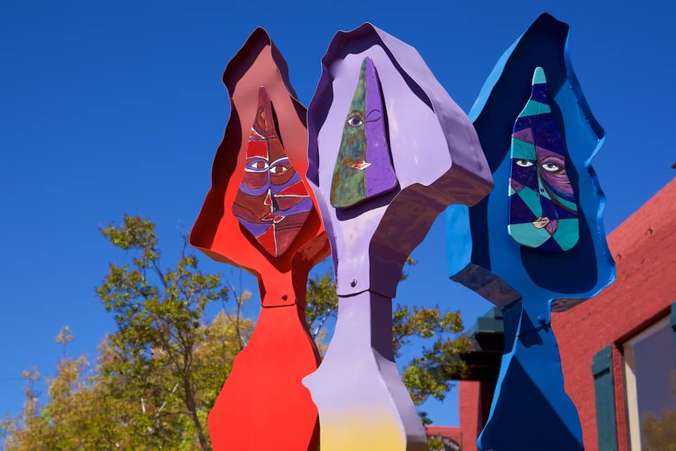 Trois sculptures abstraites aux couleurs vives, se détachant sur un ciel bleu clair.