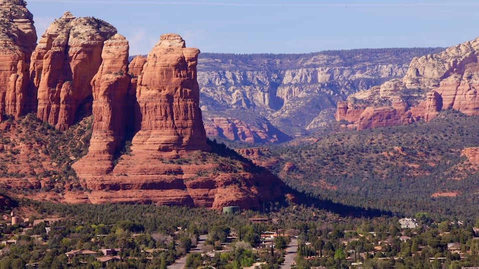 A canyon with red rock formations and a town at the base.