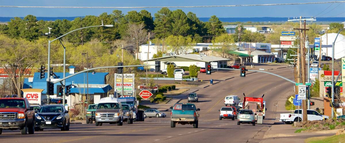 A busy intersection with multiple lanes of traffic, including cars and trucks. Visible businesses include CVS Pharmacy, a fitness center, and a Kiva Motti's. There are traffic lights and street signs indicating a speed limit of 35 mph.