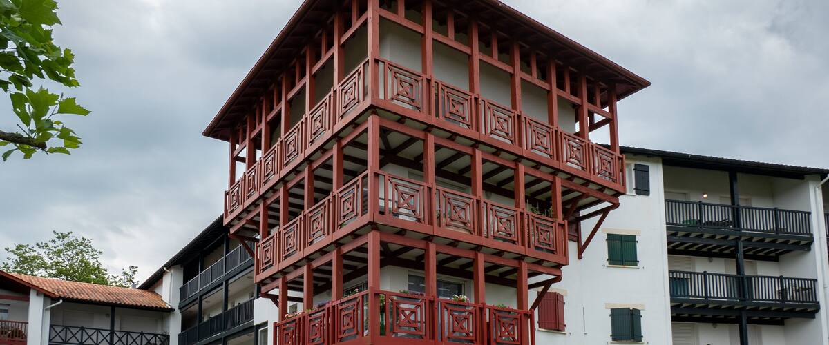 A multi-story building with a distinctive red balcony structure.