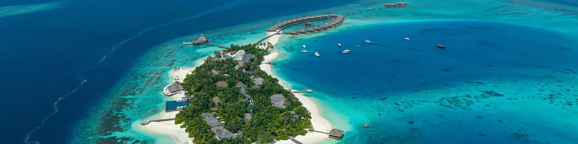 Aerial view of bungalows of a luxury hotel on Huvafen Fushi island at sunset on Maldives archipelagos.