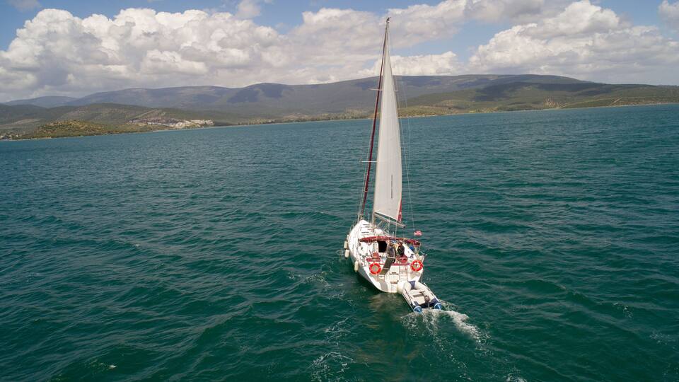 A sailboat on a calm lake with mountains in the background.