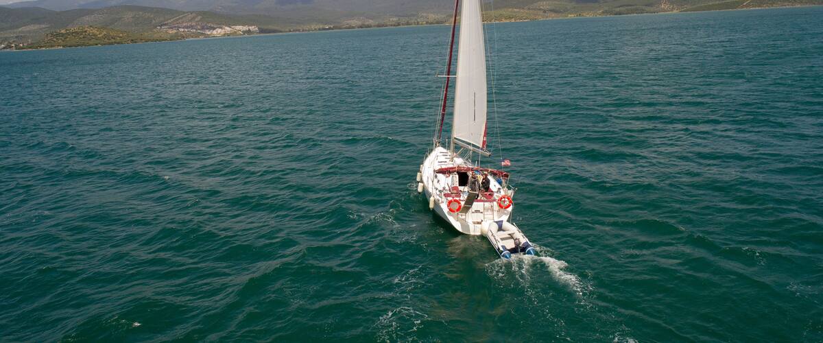 A sailboat on a calm lake with mountains in the background.