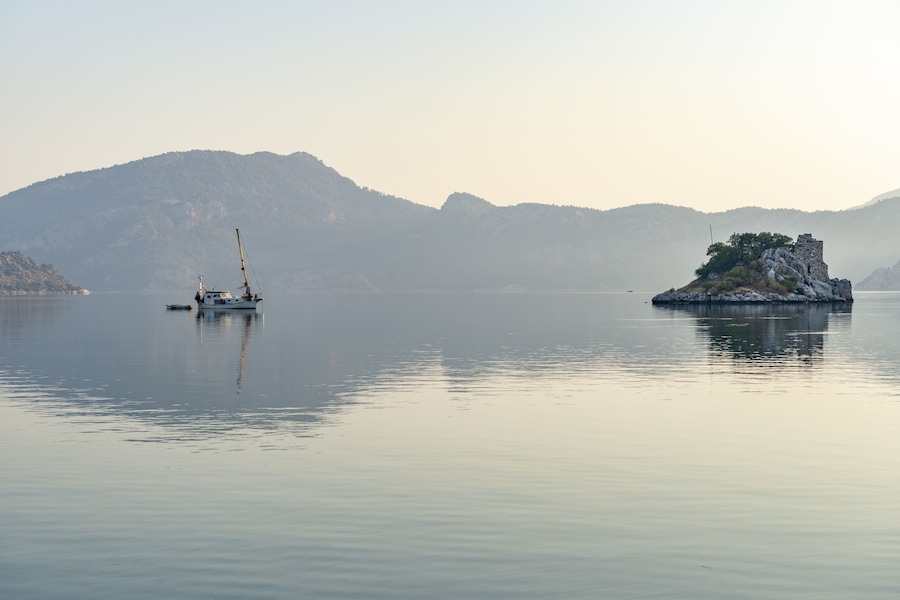 Un lago tranquilo con un bote pequeño y una isla rocosa con ruinas.