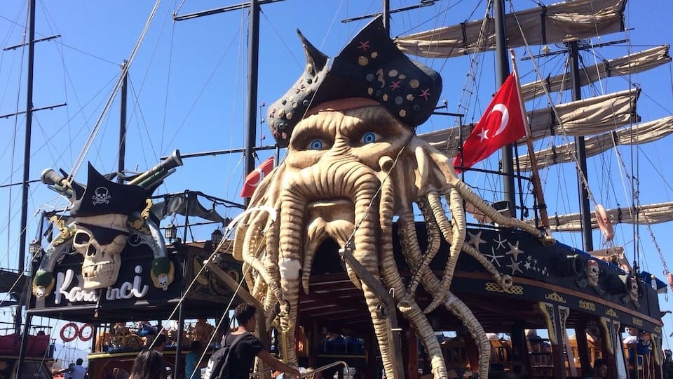 Un barco grande con una figura gigante de pulpo y una bandera pirata.