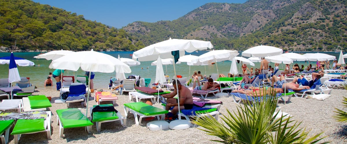 A crowded beach with white umbrellas and people sunbathing.