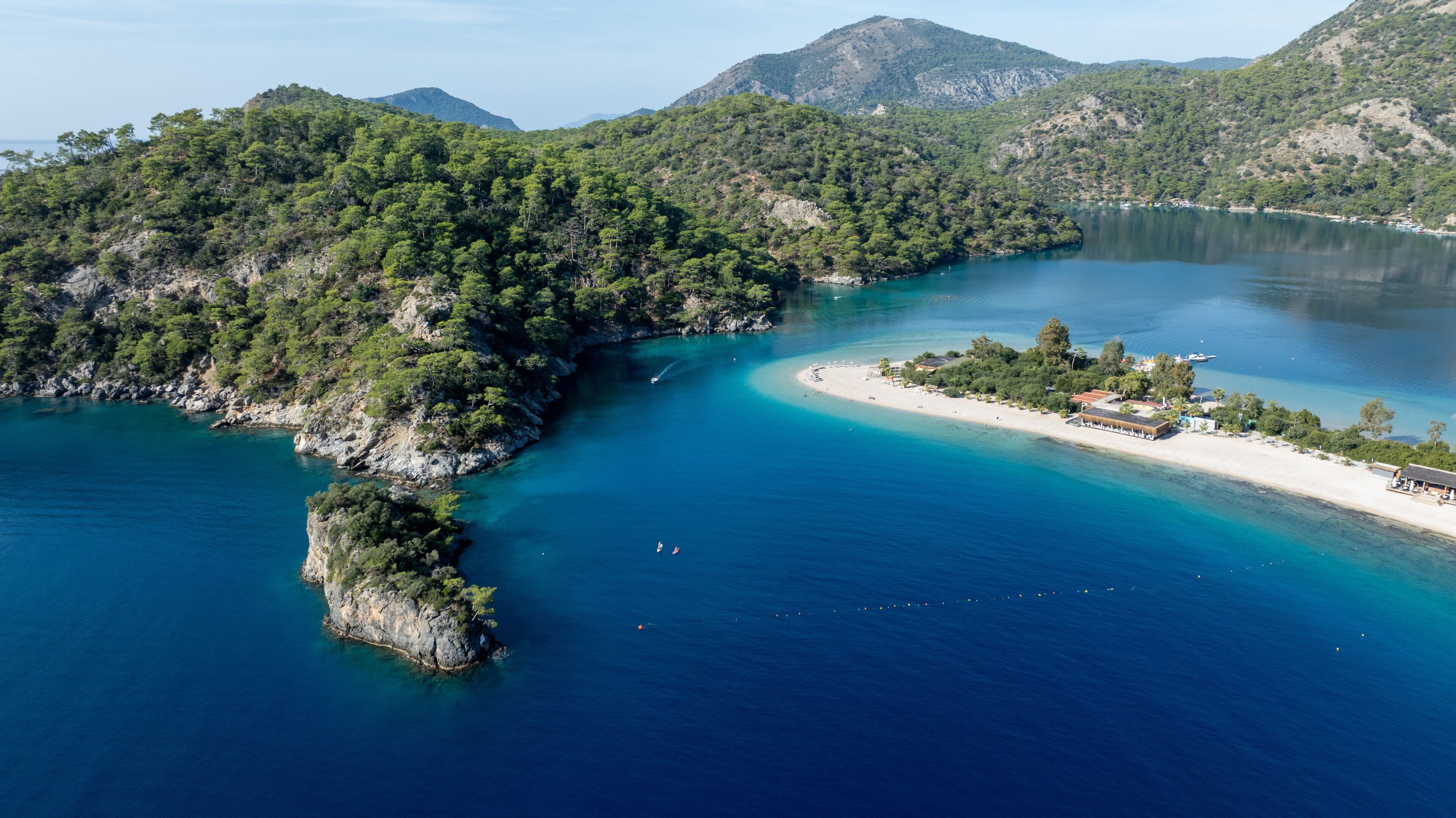 A coastal landscape with a bay, a small island, and a beach with buildings.