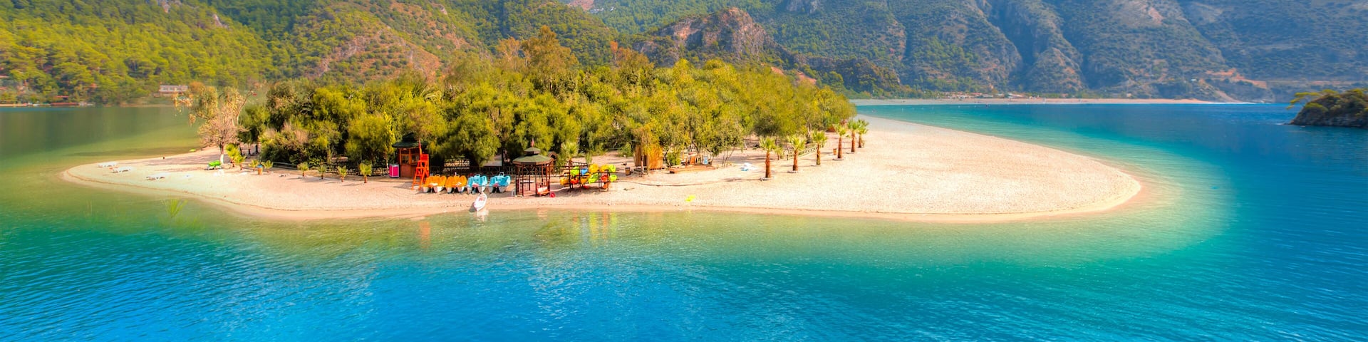 A tropical island with clear turquoise waters, surrounded by lush green mountains.