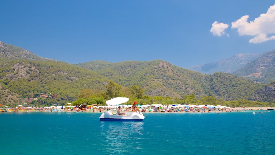 A boat on a turquoise sea with a beach and mountains in the background.