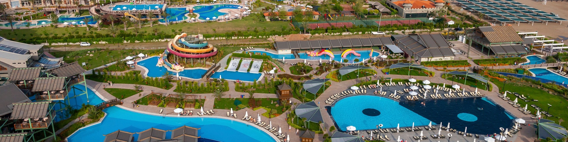 Um resort com várias piscinas, uma praia e um píer.