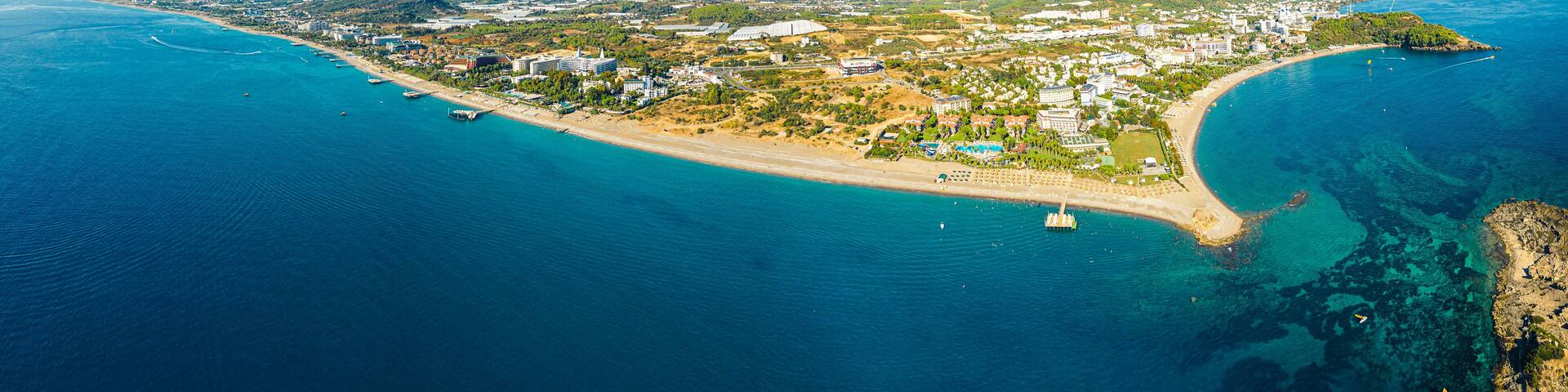 Okurcalar, Alanya, Turkey. Drone view of the wide blue transparent Mediterranean sea, reef under the water, a sandy coastline around the resort city. High quality photo