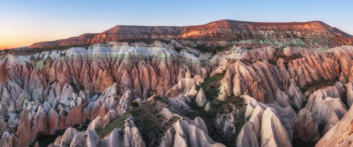 A rugged landscape with layered rock formations and a mountain in the background.