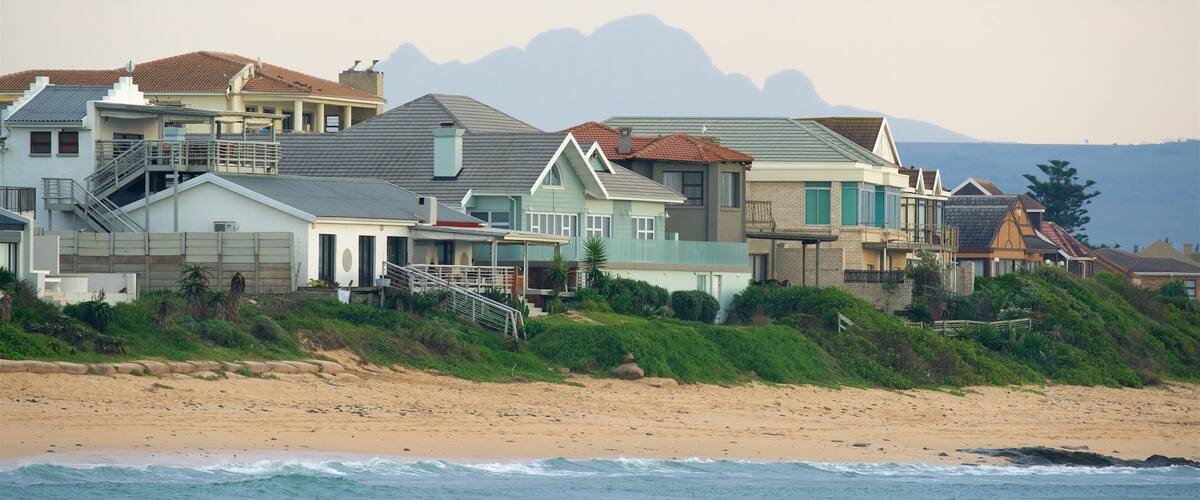 A coastal residential area with houses on a hillside overlooking the beach.