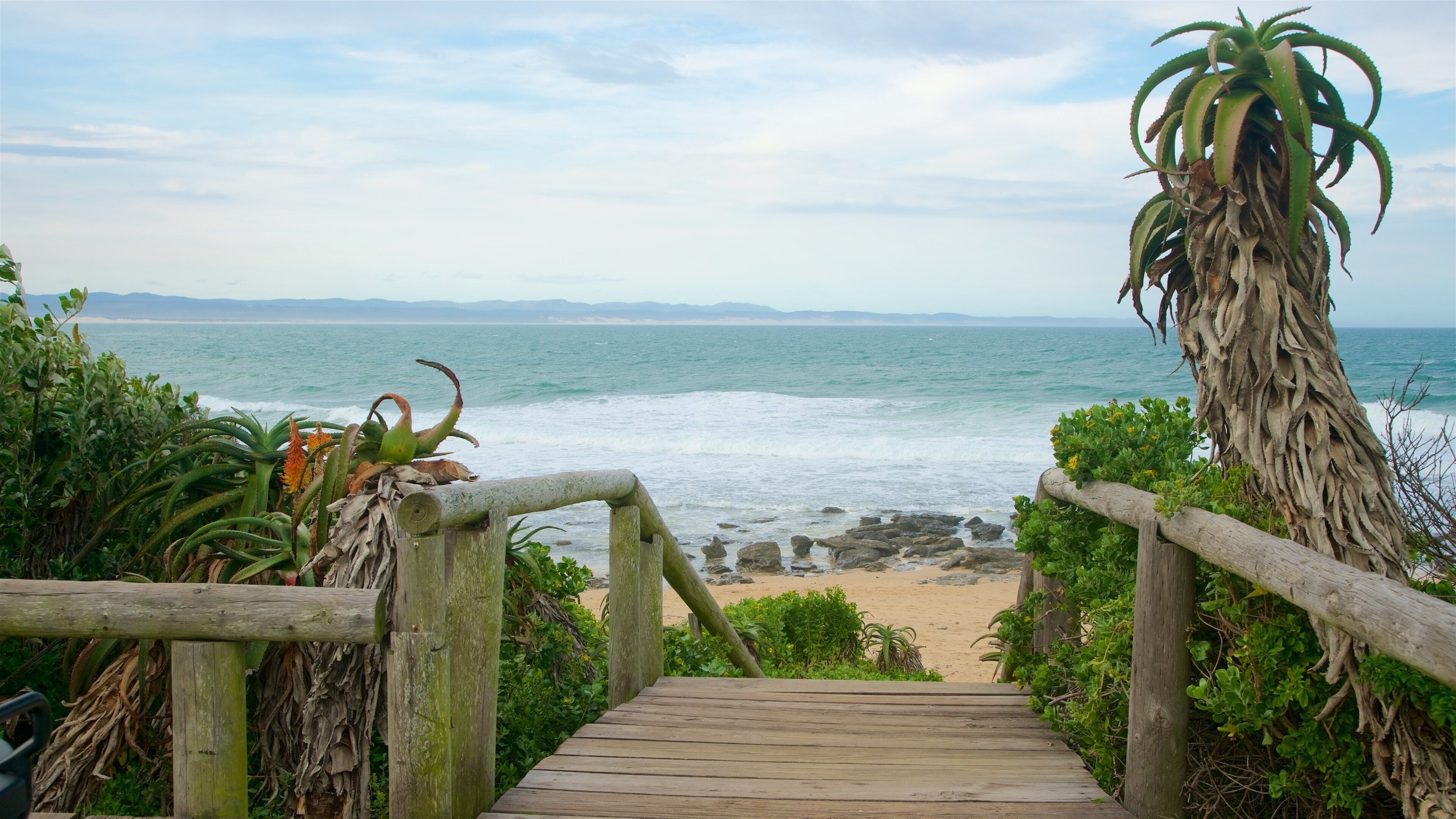 A wooden boardwalk leading to a beach with ocean views.