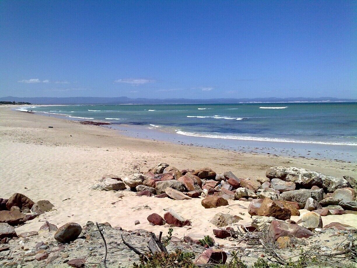 A beach with scattered rocks and waves approaching the shore.