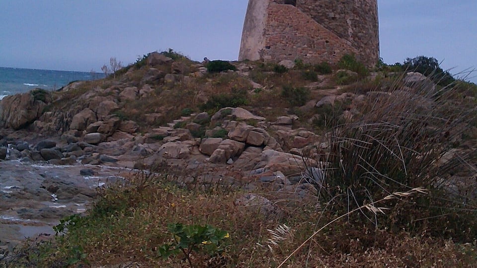 A coastal tower on a rocky outcrop with the ocean in the background.