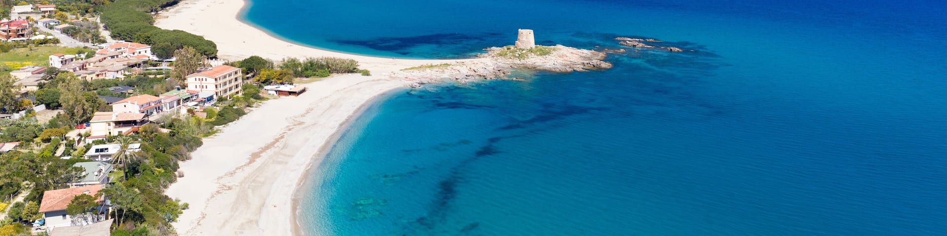 Aerial drone view of Torre di Bari, surrounded by turquoise waters and white sandy beaches along the eastern coast of Sardinia on a clear sunny day