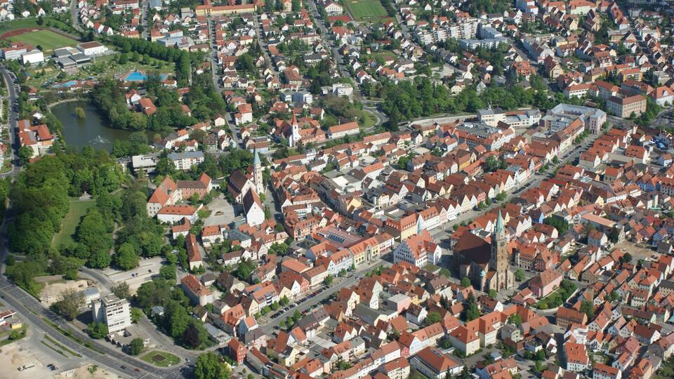 An aerial view of a densely built urban area with historic buildings, a church, and a river.
